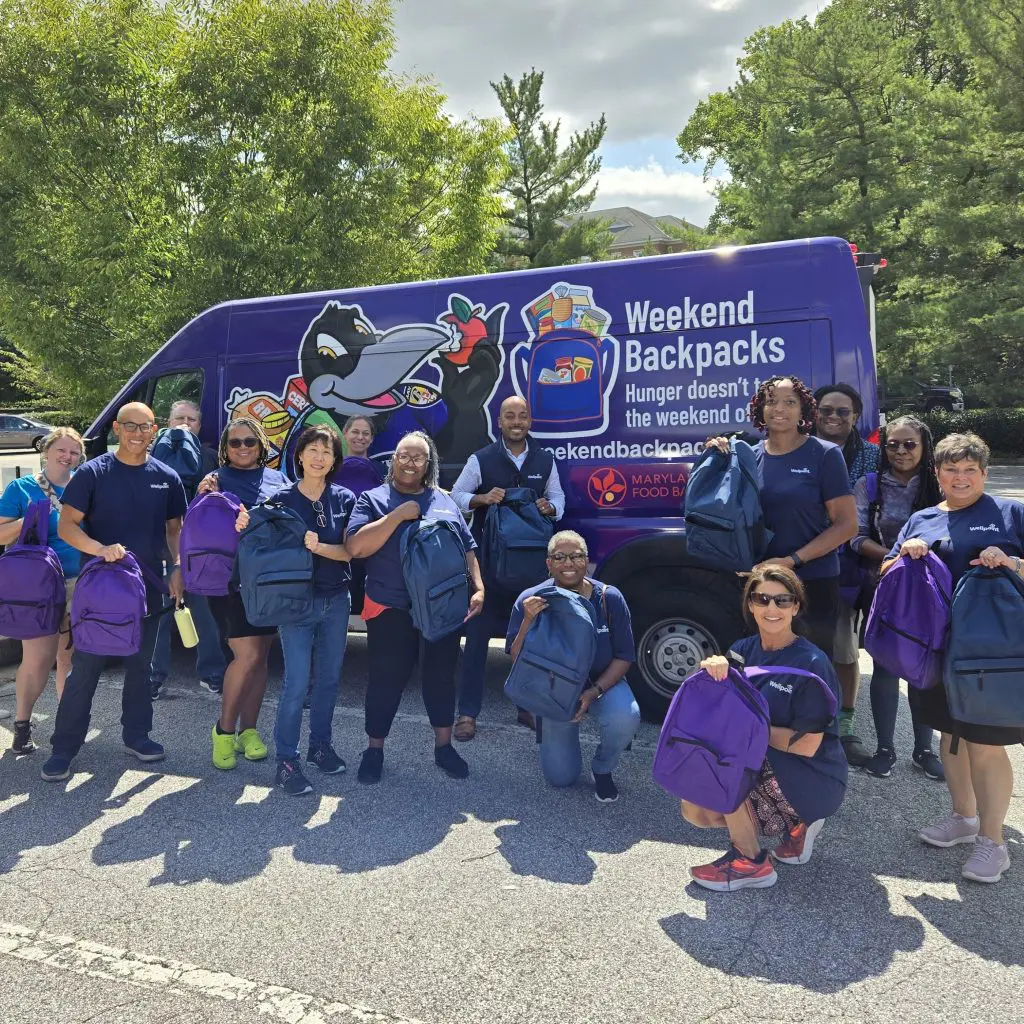 A group of people holding backpacks in front of a Weekend Backpacks branded cargo van.