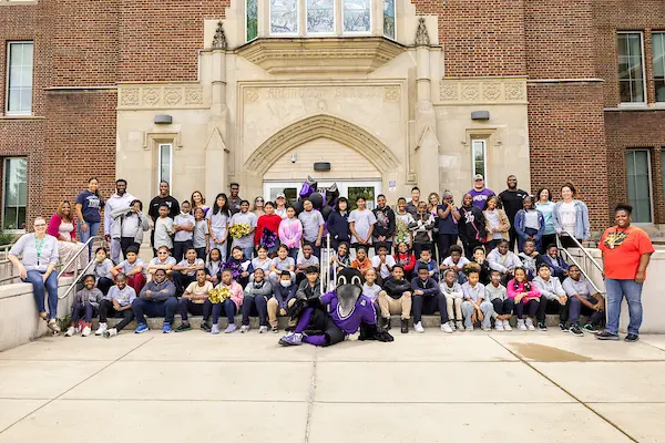 Ravens players, cheerleaders, and mascot, school staff and students, and Weekend Backpack's staff posed in front of Arlington Elementary School