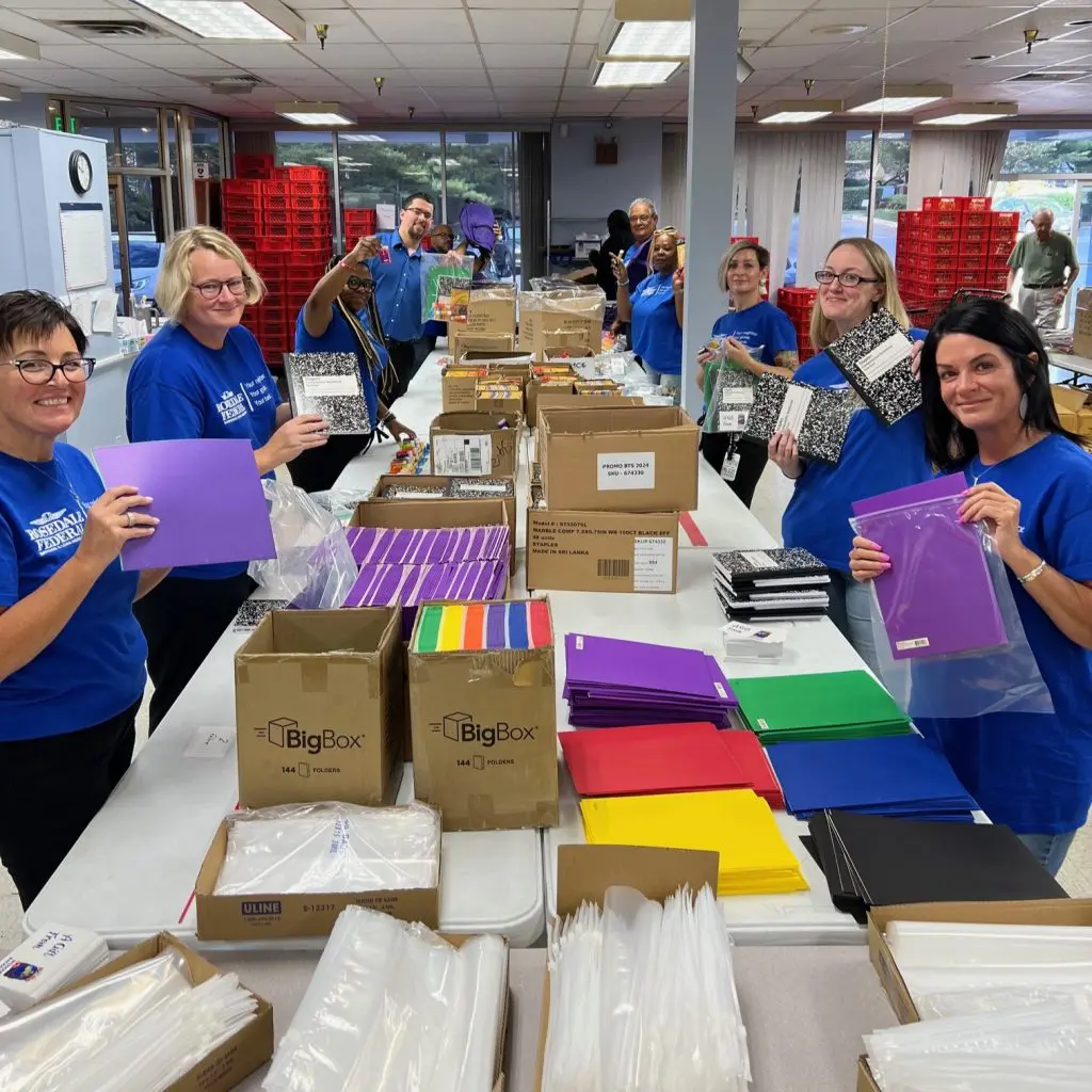 People spread out around tables filled with school supplies packing them into bags.