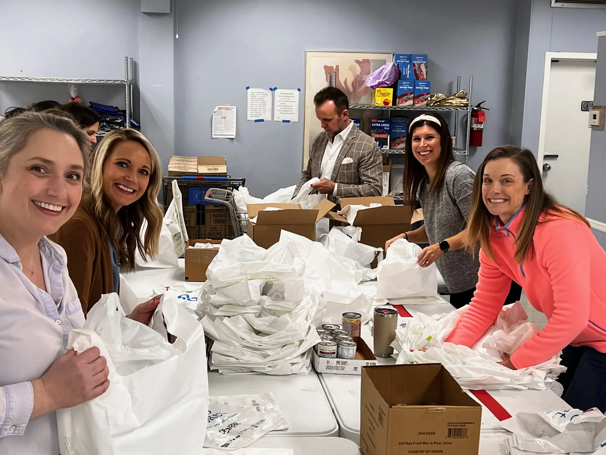 People around a table holding plastic bags.