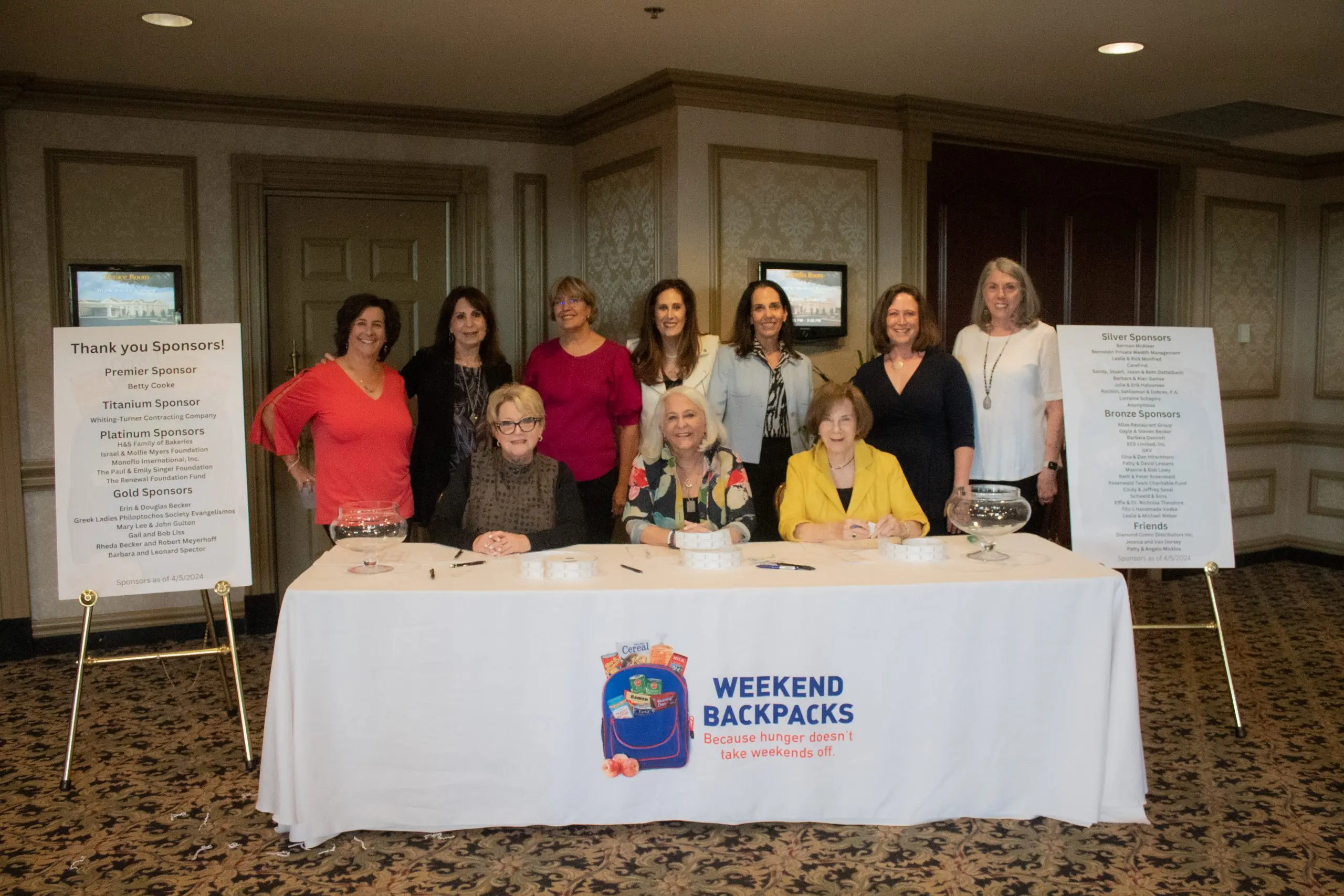 A group of women posed smiling behind a welcome table.