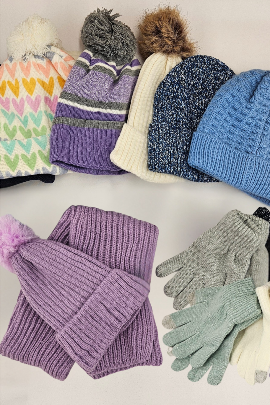 An assortment of hats, gloves and scarves in a pile on a table.