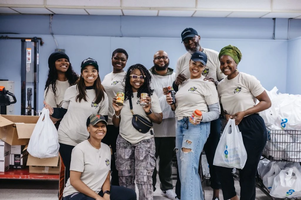 A group of people holding bags of food and food items.