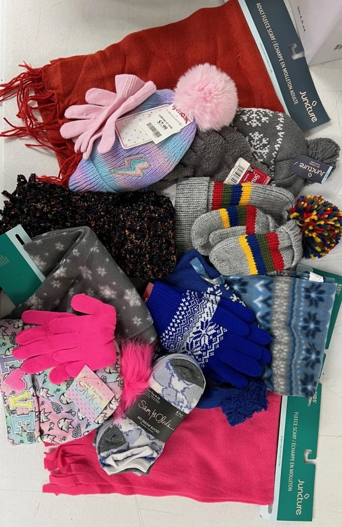 An assortment of hats, gloves and scarves in a pile on a table.