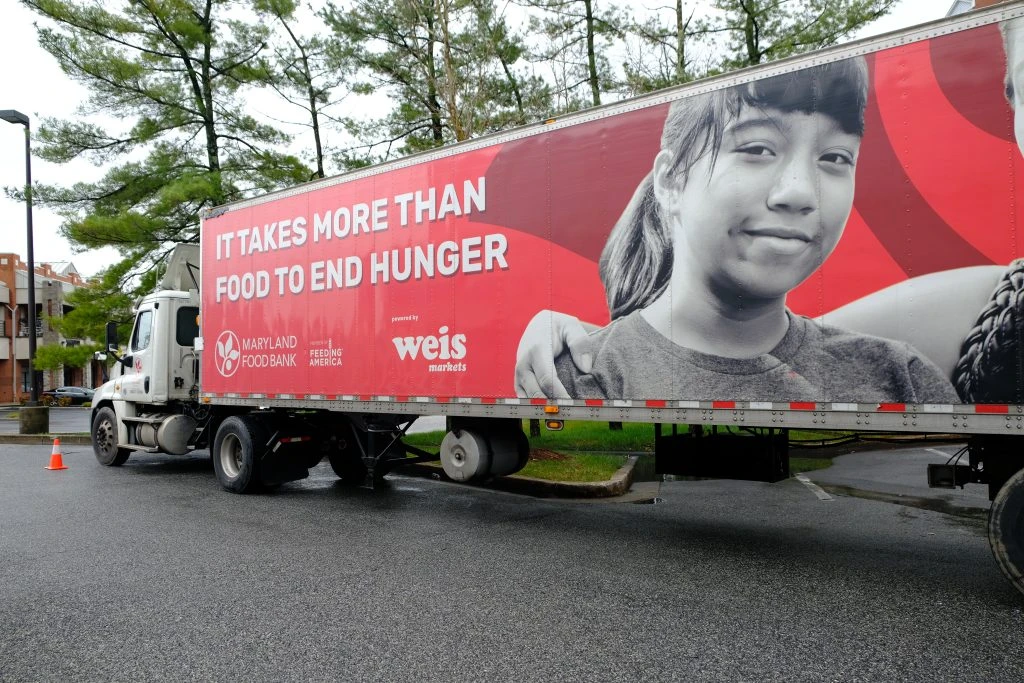 A Maryland Food Bank truck with the writing "It takes more than food to end hunger" on it in a parking lot.