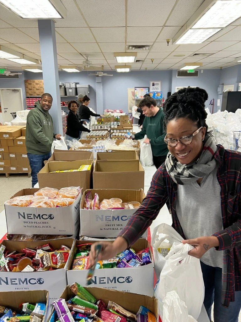 People around a table packing food into bags.