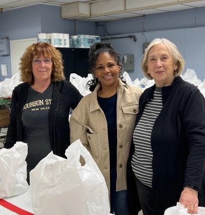 Three women posed with bags of food.